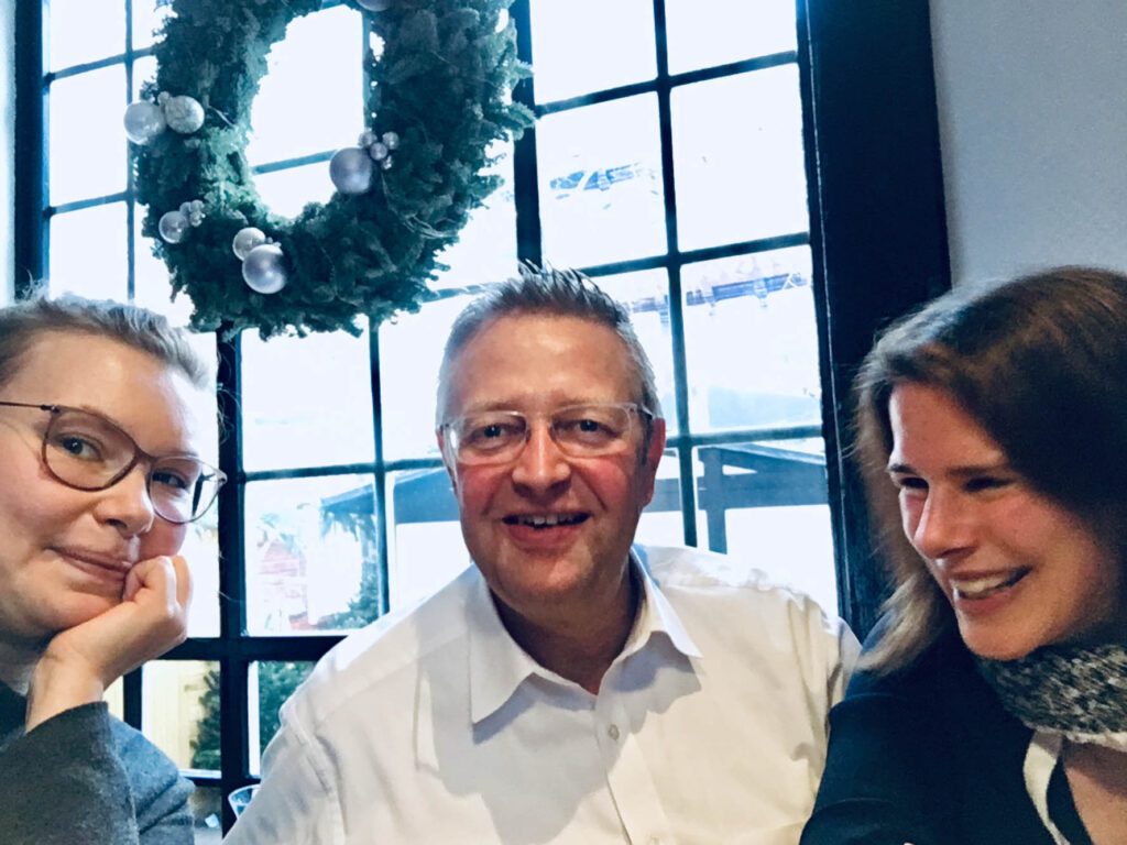 Eine Selfie-Aufnahme von Anna Brandes und zwei Lunch-Connection-Teilnehmenden – eine Frau und ein Mann – drinnen im Restaurant.