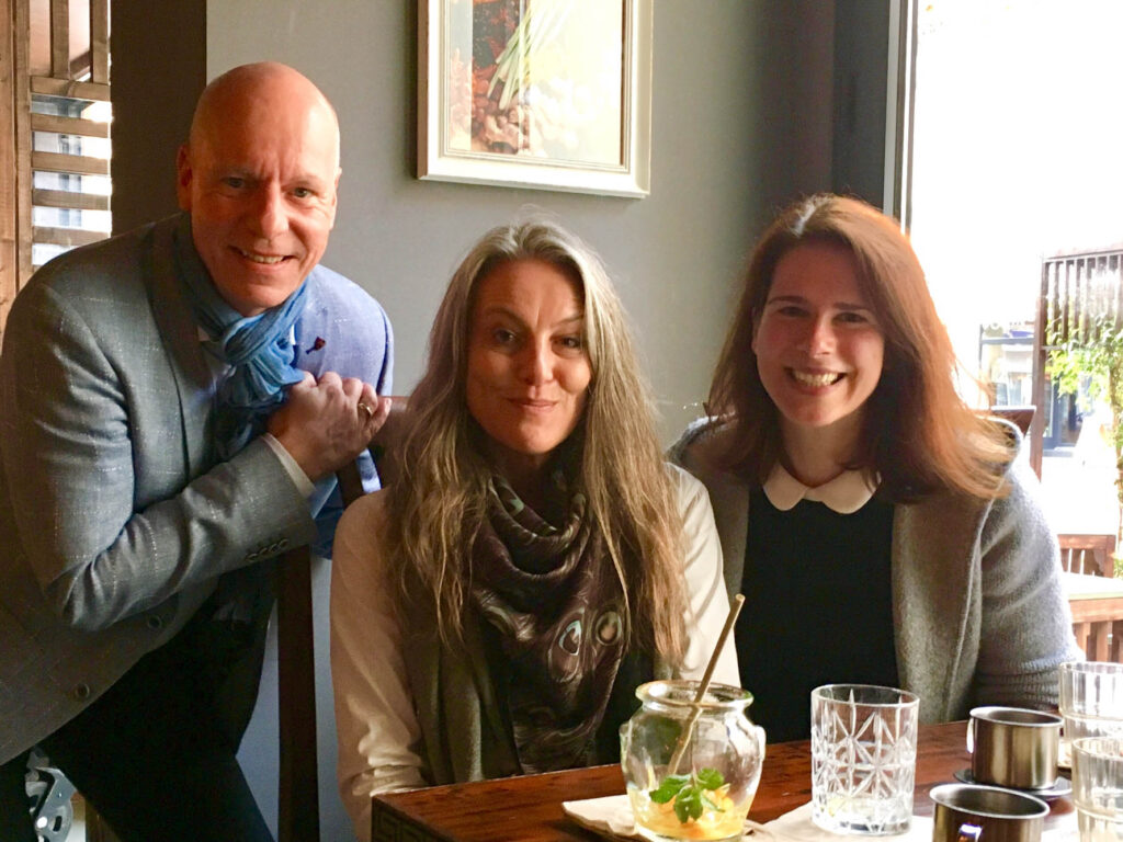Anna Brandes und zwei Lunch-Connection-Teilnehmende posieren fürs Foto am Tisch. Alle lächeln in die Kamera.